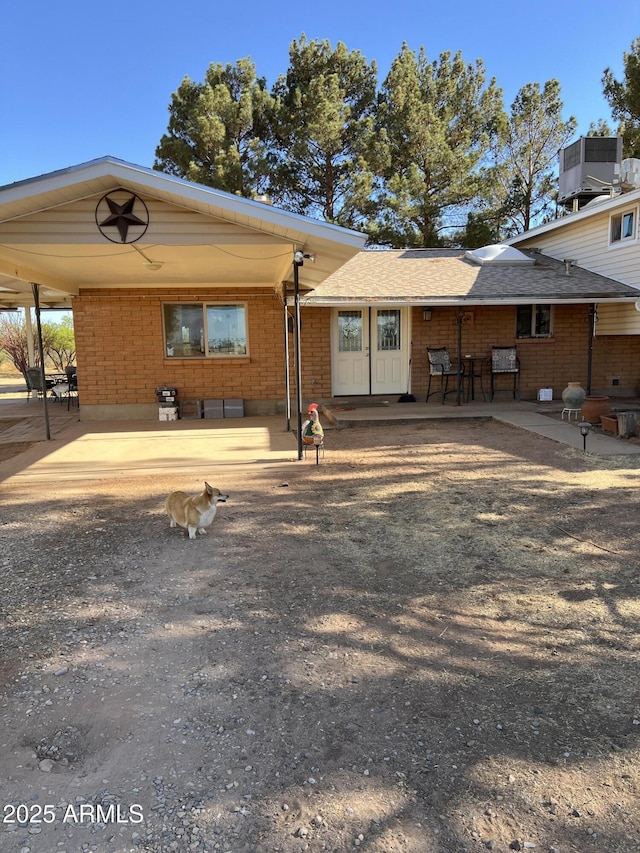 rear view of property featuring central air condition unit, a patio, and brick siding