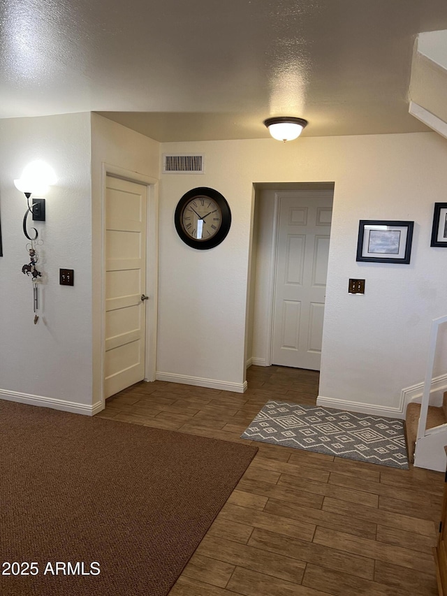 hall with baseboards, wood finished floors, and visible vents
