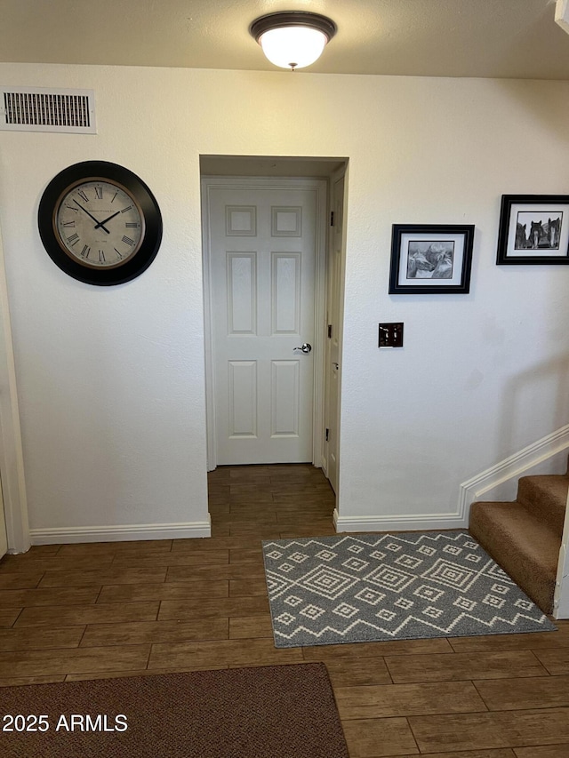 hallway featuring stairway, wood tiled floor, baseboards, and visible vents