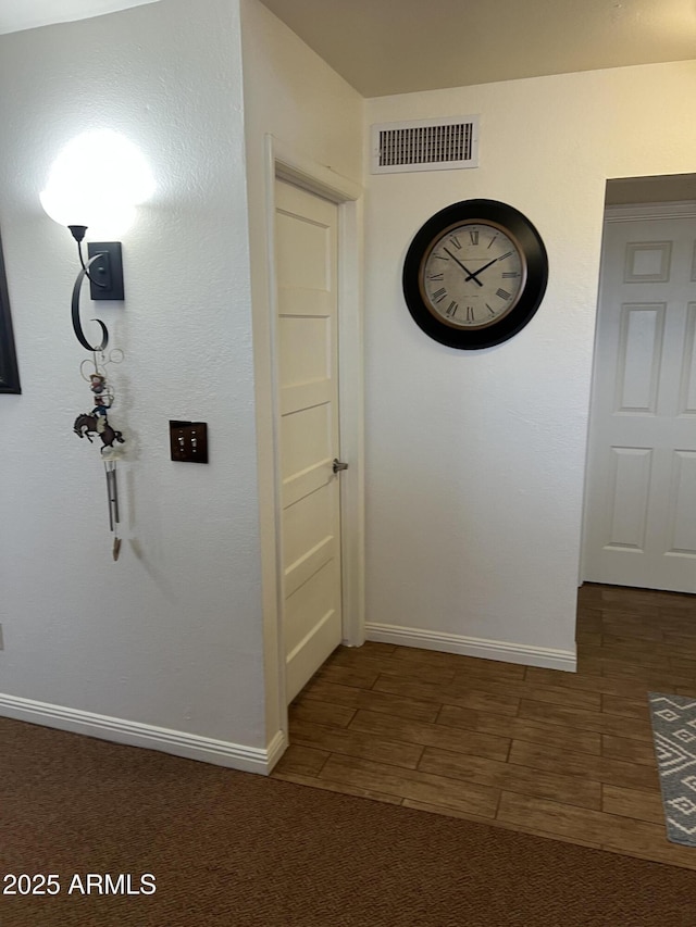 hallway with baseboards and visible vents