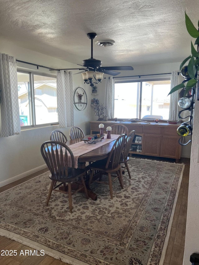 dining room with visible vents, a ceiling fan, a textured ceiling, and wood finished floors
