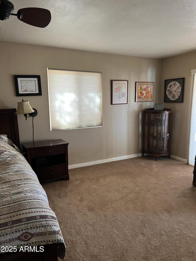 carpeted bedroom with a ceiling fan, baseboards, and a textured ceiling