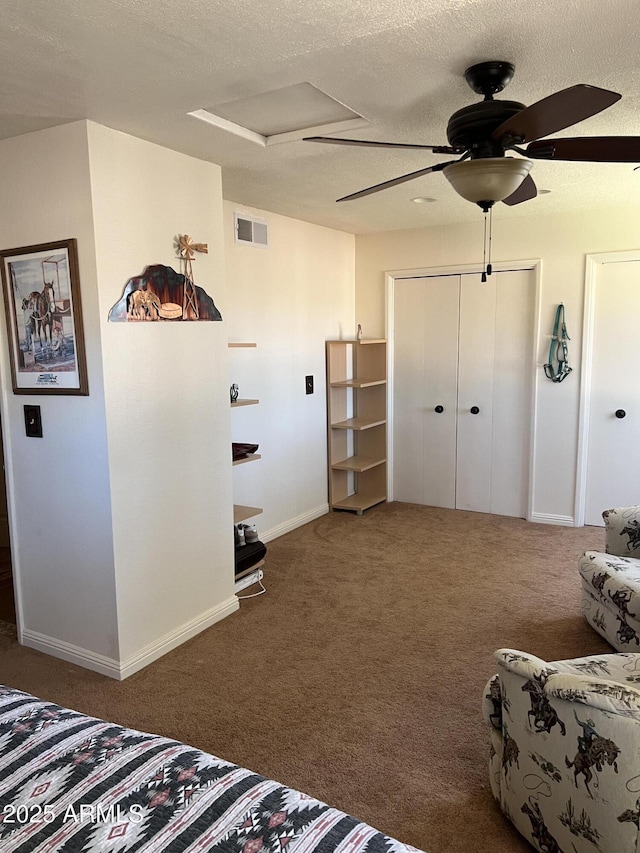 bedroom with carpet flooring, ceiling fan, attic access, baseboards, and visible vents