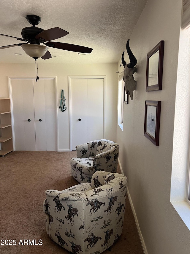 bedroom with carpet floors, two closets, baseboards, ceiling fan, and a textured ceiling