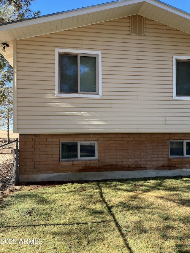 view of side of home featuring fence and a yard