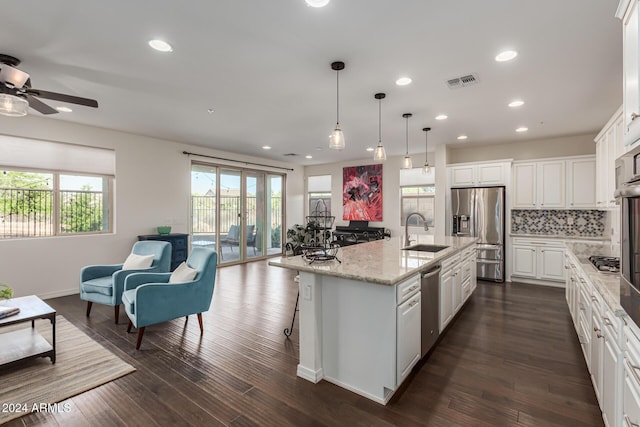 kitchen featuring appliances with stainless steel finishes, a sink, open floor plan, a ceiling fan, and white cabinets