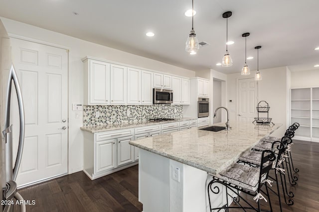 kitchen with appliances with stainless steel finishes, a sink, dark wood finished floors, a kitchen breakfast bar, and recessed lighting