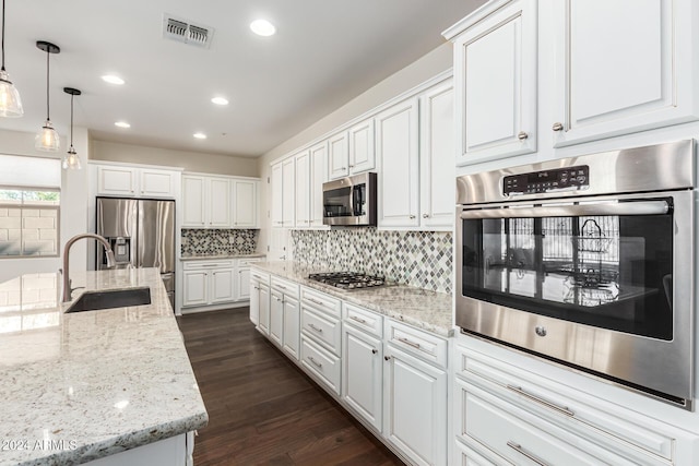 kitchen featuring stainless steel appliances, a sink, white cabinetry, decorative backsplash, and recessed lighting