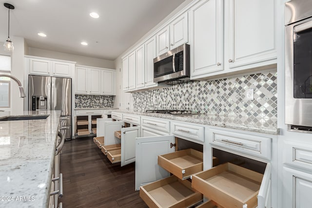 kitchen with appliances with stainless steel finishes, dark hardwood / wood-style flooring, tasteful backsplash, pendant lighting, and white cabinetry