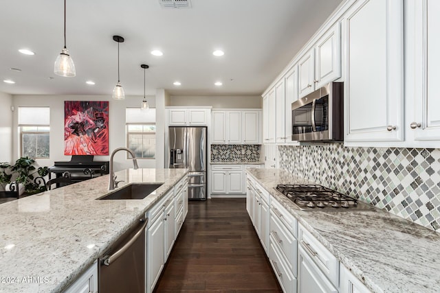 kitchen with a sink, appliances with stainless steel finishes, white cabinets, recessed lighting, and hanging light fixtures