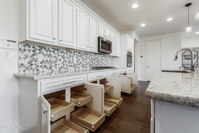 kitchen with pendant lighting, white cabinets, dark wood-type flooring, and appliances with stainless steel finishes