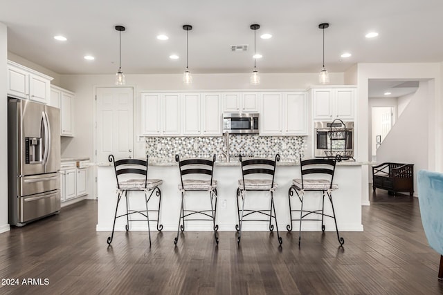 kitchen featuring appliances with stainless steel finishes, white cabinetry, a breakfast bar, tasteful backsplash, and dark wood-style flooring