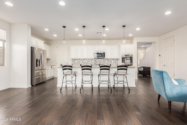 kitchen featuring appliances with stainless steel finishes, white cabinetry, decorative backsplash, recessed lighting, and a kitchen bar
