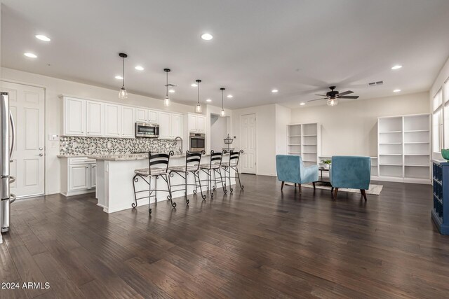 kitchen with appliances with stainless steel finishes, recessed lighting, a ceiling fan, white cabinets, and an island with sink