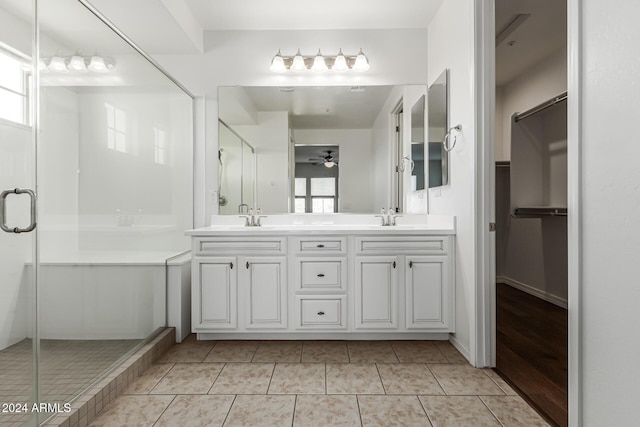 bathroom featuring a stall shower, a walk in closet, ceiling fan, and double vanity