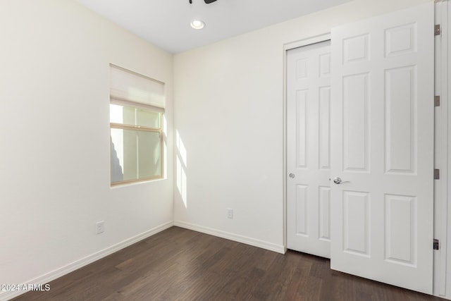 unfurnished bedroom featuring dark wood-style floors, a closet, baseboards, and recessed lighting