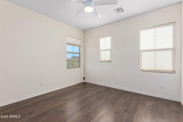 spare room with dark wood-style flooring, ceiling fan, and baseboards