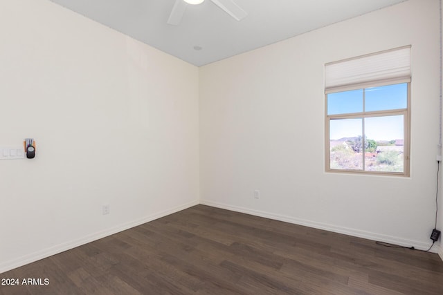 empty room with dark wood-style floors, baseboards, and ceiling fan