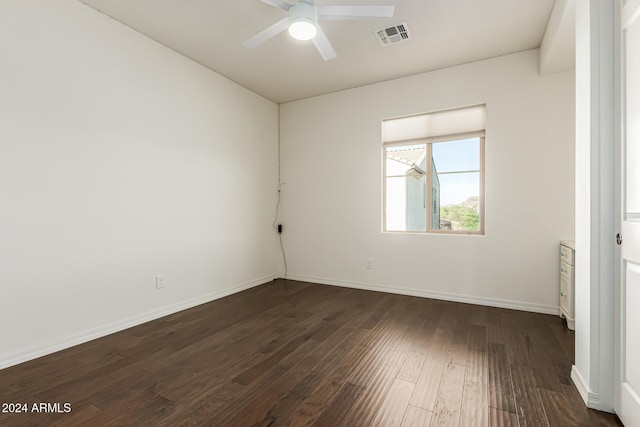 empty room featuring dark wood-style flooring, a ceiling fan, and baseboards
