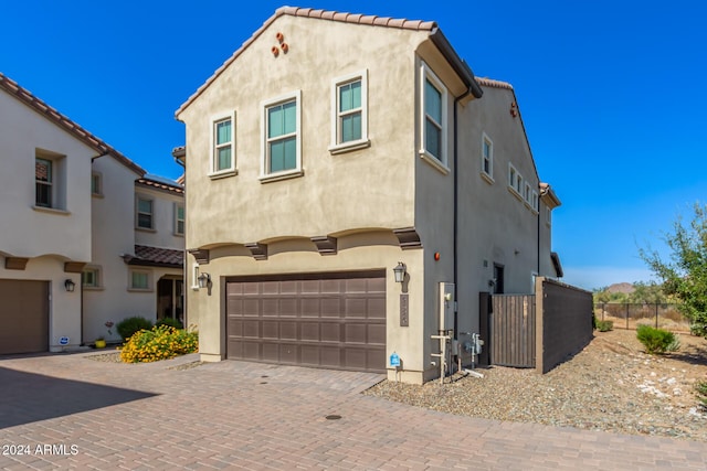 view of front of home with an attached garage, fence, stucco siding, and decorative driveway