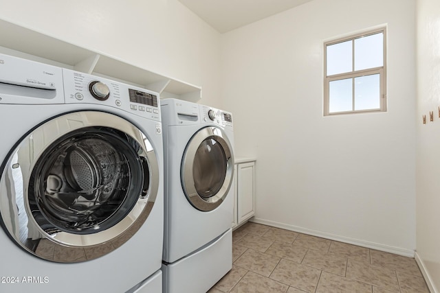 laundry room featuring washer and clothes dryer, baseboards, cabinet space, and light tile patterned floors