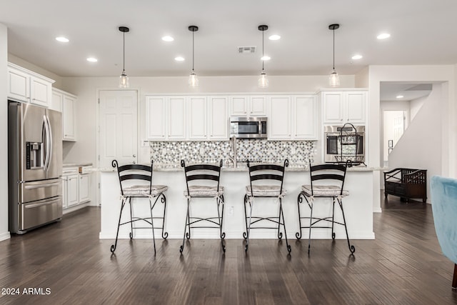 kitchen with a center island with sink, white cabinetry, hanging light fixtures, and stainless steel appliances