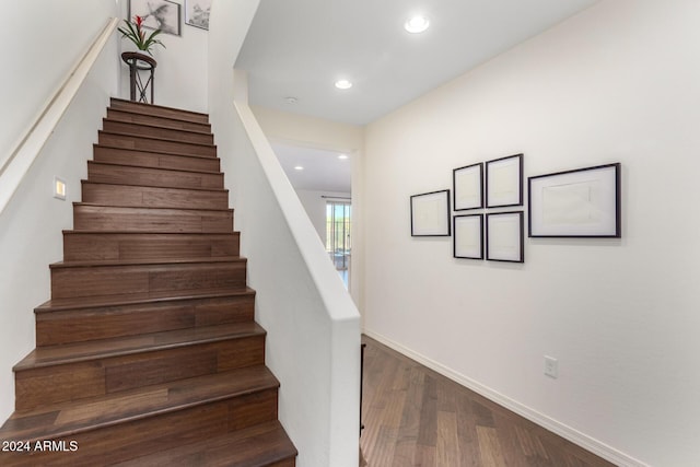 stairway featuring wood finished floors, baseboards, and recessed lighting