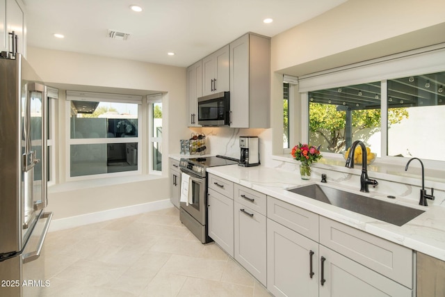 kitchen with light stone counters, sink, plenty of natural light, and appliances with stainless steel finishes