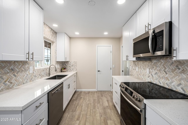 kitchen featuring a sink, white cabinetry, appliances with stainless steel finishes, and light wood finished floors