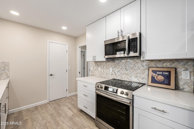 kitchen with light stone counters, stainless steel appliances, backsplash, and light wood finished floors