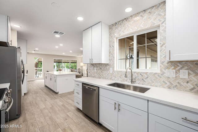 kitchen with visible vents, light wood finished floors, a sink, appliances with stainless steel finishes, and tasteful backsplash