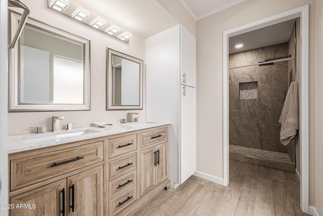 full bathroom with double vanity, wood finished floors, a tile shower, and a sink