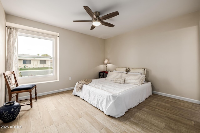 bedroom featuring baseboards, wood finished floors, and a ceiling fan