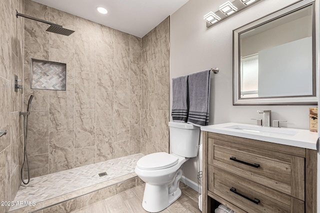 bathroom featuring tiled shower, toilet, and vanity