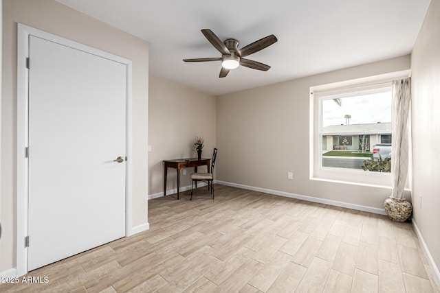 unfurnished room featuring baseboards, light wood-type flooring, and a ceiling fan