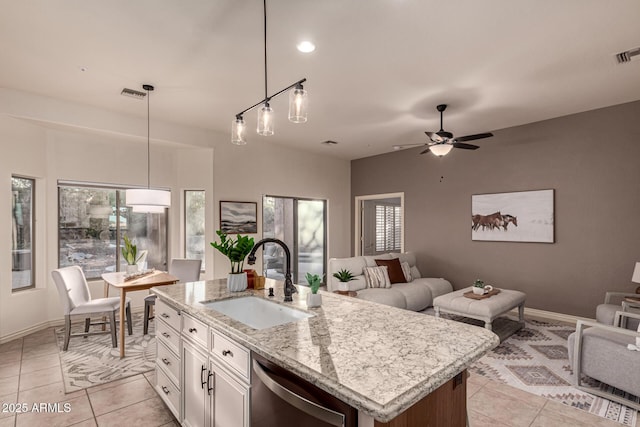 kitchen featuring decorative light fixtures, white cabinetry, sink, and a kitchen island with sink