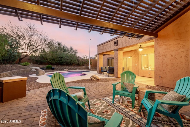 patio terrace at dusk featuring ceiling fan and a pergola