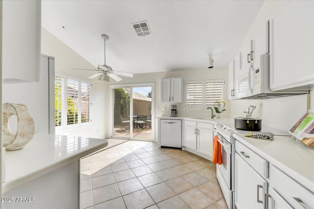 kitchen featuring lofted ceiling, light tile patterned floors, white appliances, sink, and white cabinetry