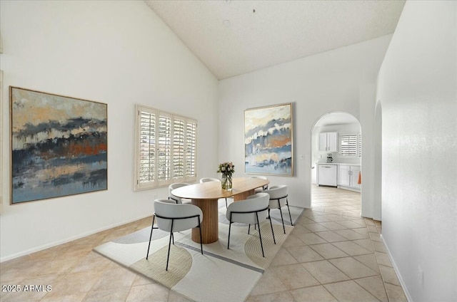 dining area featuring light tile patterned floors and high vaulted ceiling