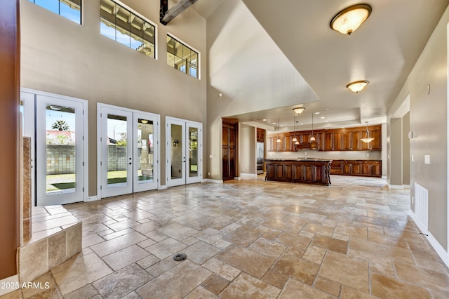 unfurnished living room with a high ceiling, a tray ceiling, and french doors