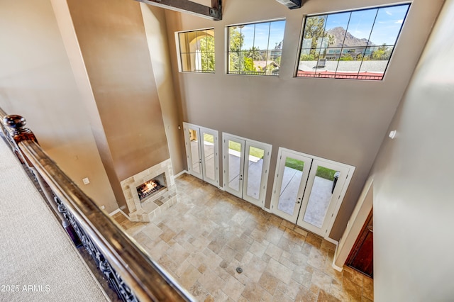 entryway with a high ceiling, a wealth of natural light, a fireplace, and french doors