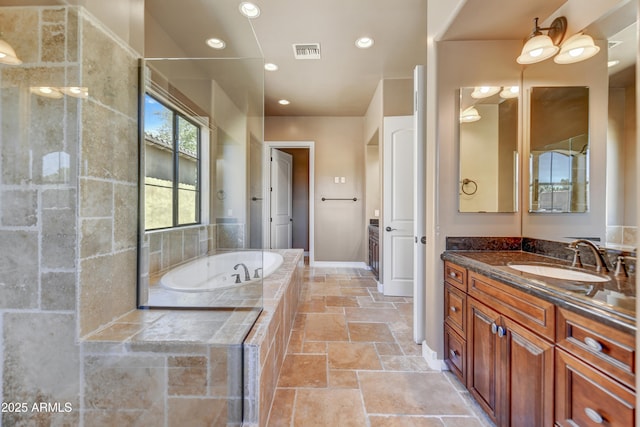 bathroom featuring vanity and tiled bath
