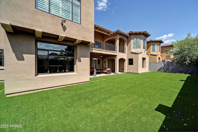 rear view of house featuring a balcony, outdoor lounge area, and a lawn
