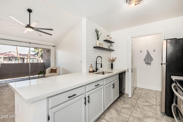 kitchen featuring light countertops, appliances with stainless steel finishes, white cabinets, a sink, and a peninsula