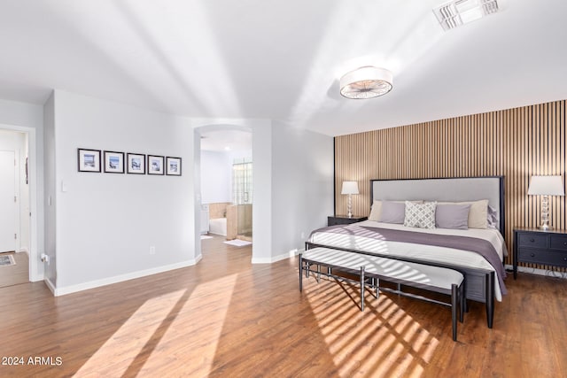 bedroom with ensuite bath and hardwood / wood-style floors