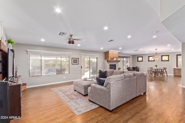 living room with a large fireplace, ceiling fan, and hardwood / wood-style floors