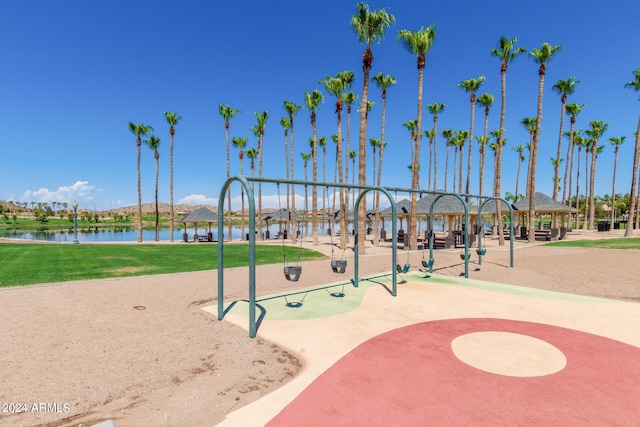 view of home's community with a playground, a yard, and a water view