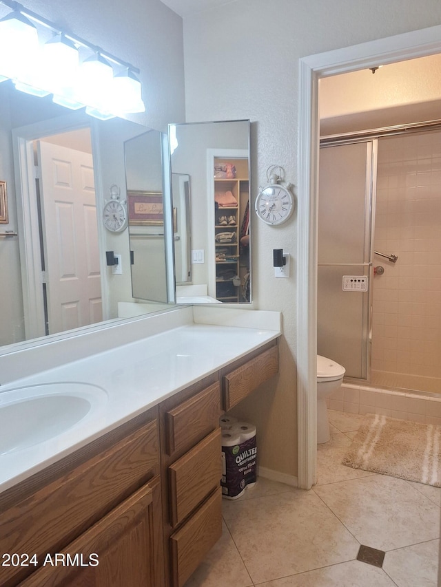 bathroom featuring tile patterned flooring, toilet, vanity, and walk in shower