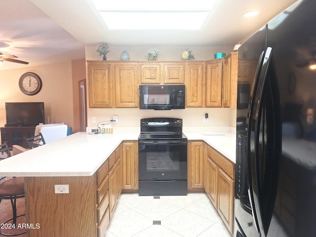 kitchen featuring black appliances, a breakfast bar, ceiling fan, and kitchen peninsula