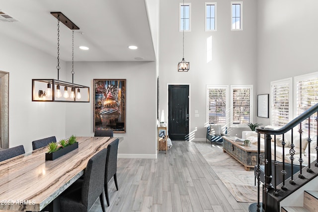 dining area featuring a towering ceiling and light hardwood / wood-style flooring